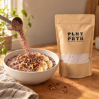 Chocolate protein powder being poured into breakfast. Full bag with sustainable packaging in the background